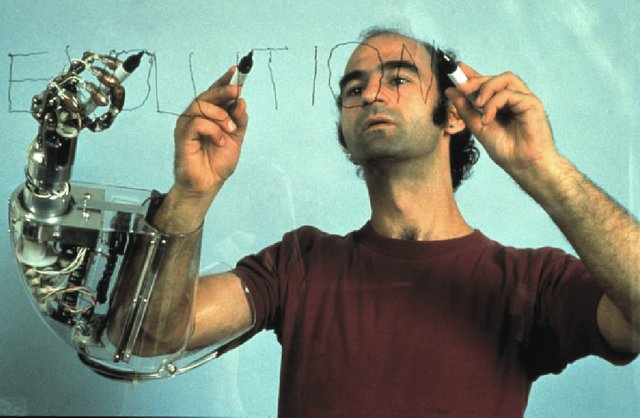 man with robot arm attached to arm writing evolution